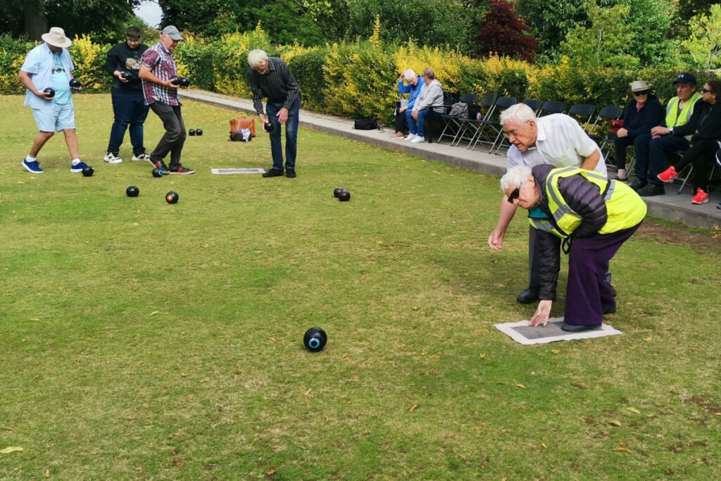 Visually impaired players and sighted volunteers playing bowls on grass