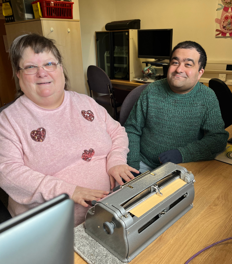 A visually impaired Braille learner using a Perkins brailler with her tutor looking on