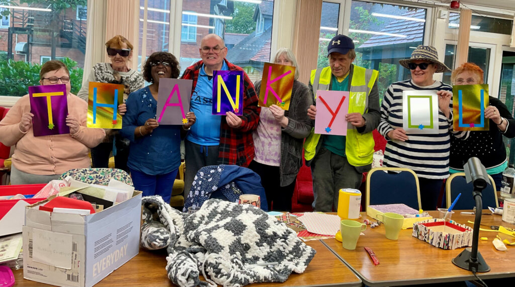 Eight members of Craft group holding handmade letters spelling out Thank You