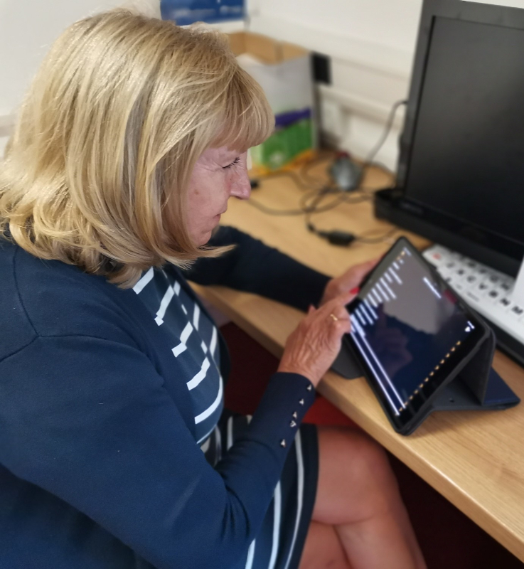 A woman seated at a desk using an iPad