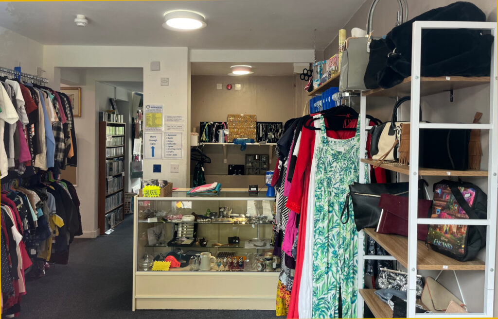 The interior of Earlsdon charity shop with racks of clothes, shelves of bags and the shop counter