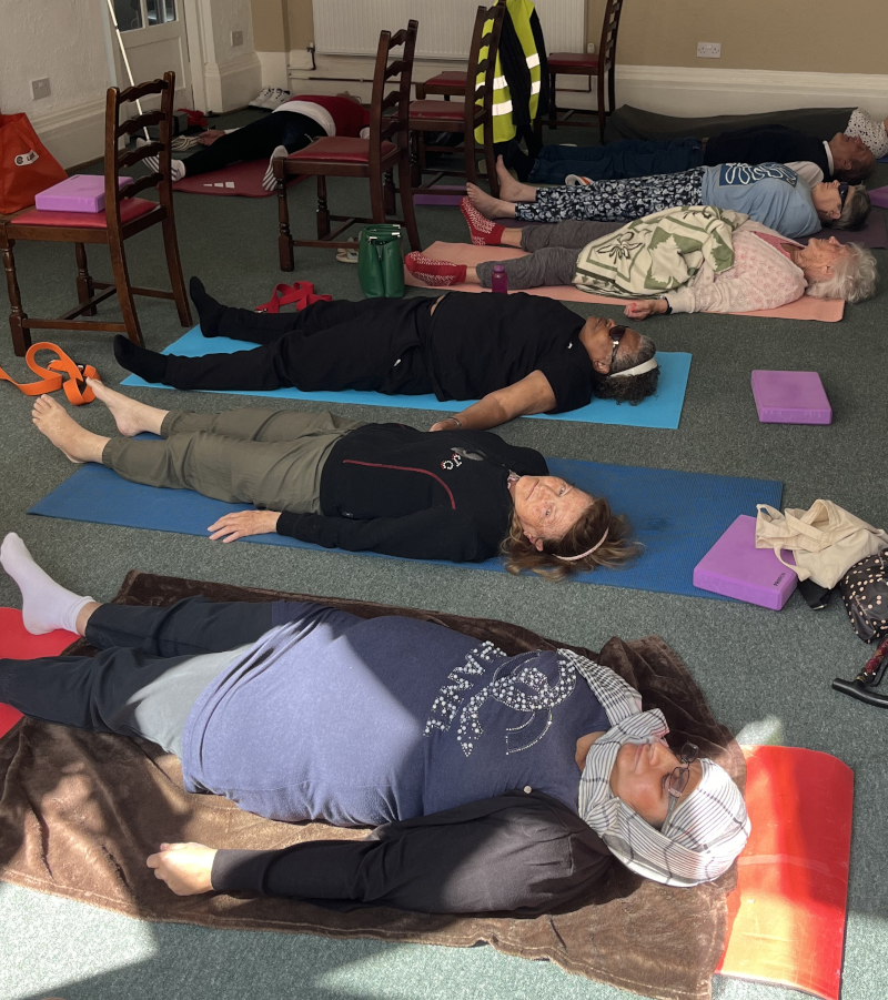 Six people lying on yoga mats